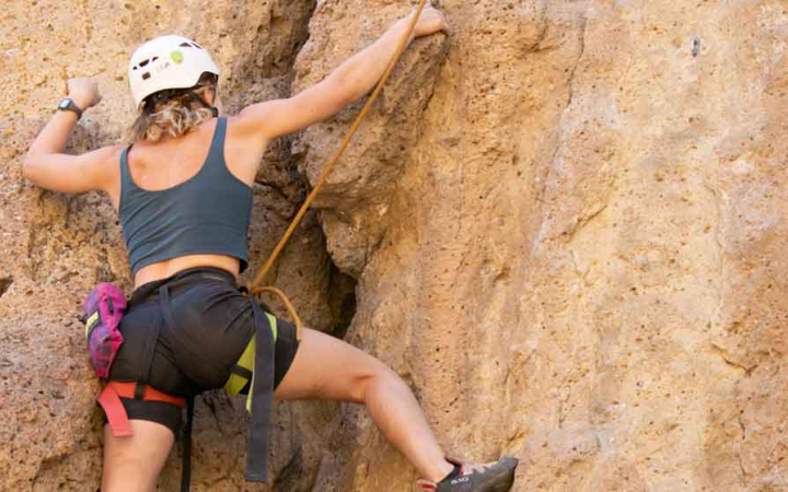 woman navigates rock while climbing on an outward bound course for women